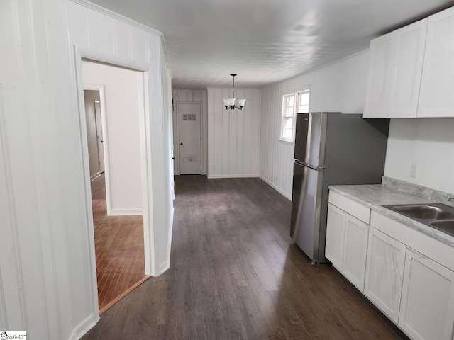 kitchen featuring an inviting chandelier, dark hardwood / wood-style flooring, hanging light fixtures, white cabinets, and sink