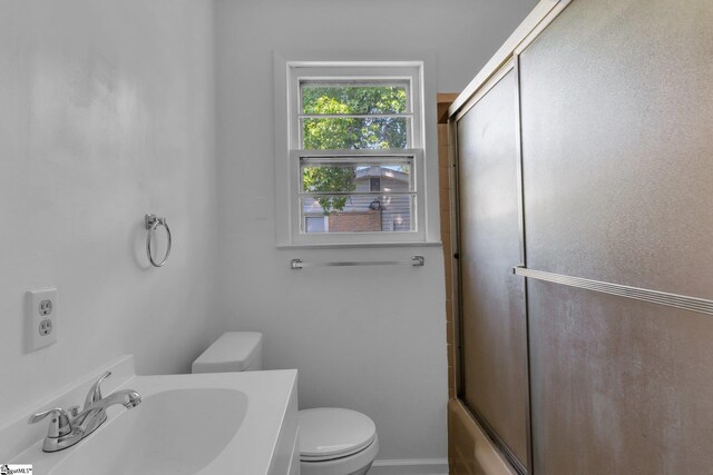 full bathroom with combined bath / shower with glass door, vanity, and toilet