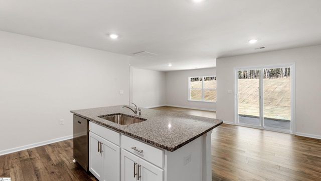 kitchen with a center island with sink, sink, stainless steel dishwasher, dark stone countertops, and dark hardwood / wood-style flooring