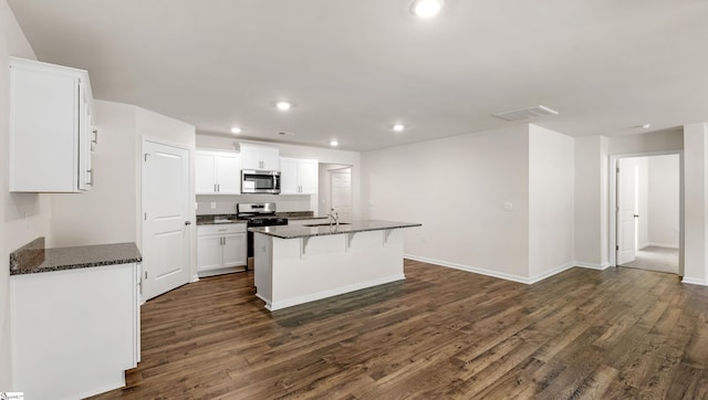 kitchen featuring appliances with stainless steel finishes, dark hardwood / wood-style flooring, a kitchen island with sink, sink, and white cabinets