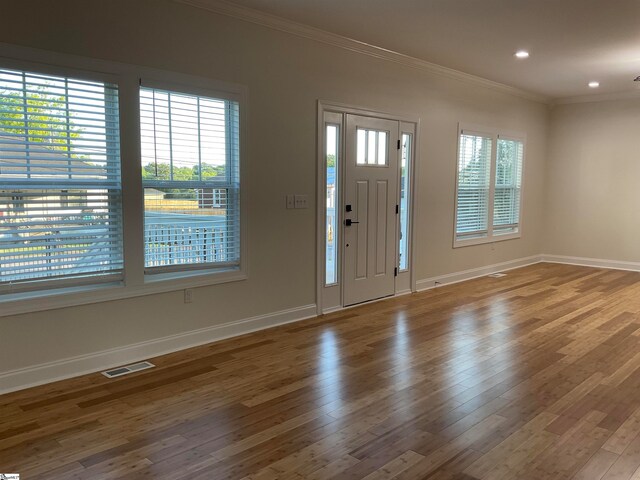 entrance foyer featuring wood-type flooring, plenty of natural light, and crown molding