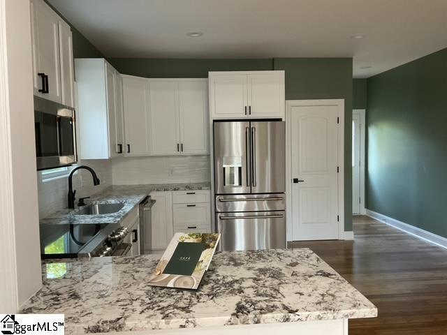 kitchen featuring white cabinets, dark hardwood / wood-style flooring, backsplash, appliances with stainless steel finishes, and sink