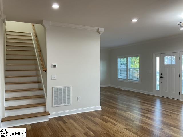 foyer with ornamental molding and dark hardwood / wood-style flooring