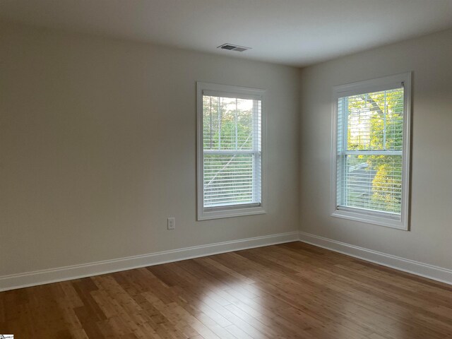 unfurnished room with a wealth of natural light and hardwood / wood-style floors