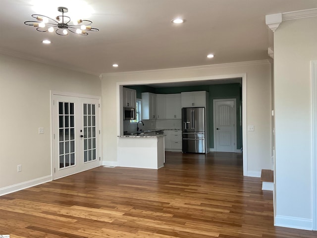 unfurnished living room featuring sink, hardwood / wood-style floors, crown molding, a chandelier, and french doors