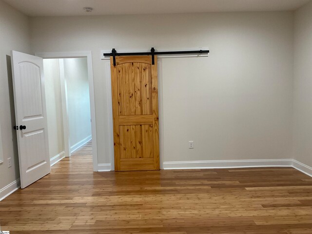 unfurnished room with hardwood / wood-style flooring and a barn door