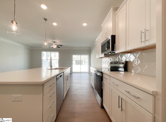 kitchen featuring a kitchen island with sink, tasteful backsplash, white cabinetry, stainless steel appliances, and crown molding