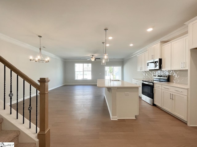 kitchen featuring tasteful backsplash, stainless steel appliances, crown molding, and an island with sink