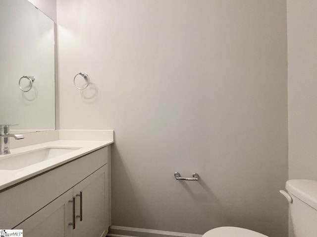 bathroom featuring vanity, toilet, and baseboards