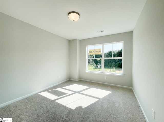 spare room with carpet, visible vents, and baseboards