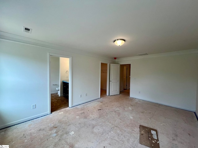 unfurnished bedroom with a walk in closet, a closet, crown molding, and ensuite bathroom