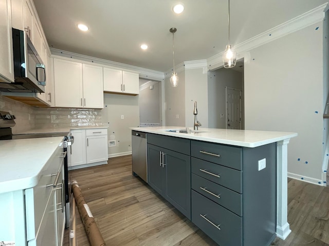 kitchen with stainless steel appliances, white cabinets, an island with sink, and light hardwood / wood-style flooring