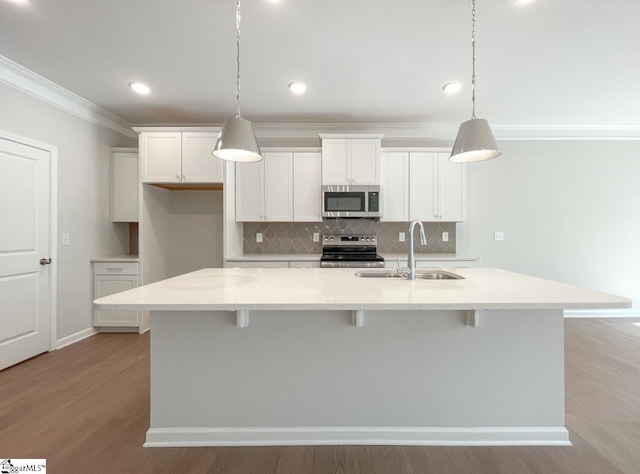 kitchen featuring light stone counters, appliances with stainless steel finishes, a kitchen island with sink, and pendant lighting