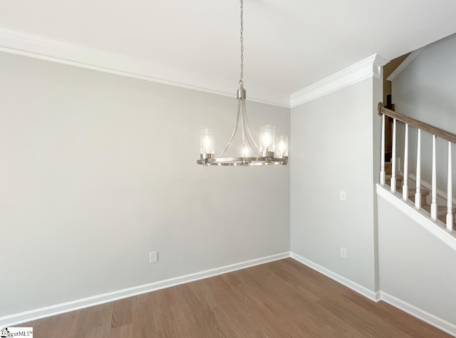 unfurnished dining area with hardwood / wood-style flooring, crown molding, and a notable chandelier