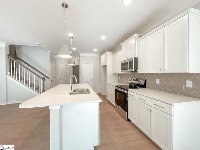 kitchen featuring decorative light fixtures, white cabinetry, sink, a kitchen island with sink, and stainless steel appliances