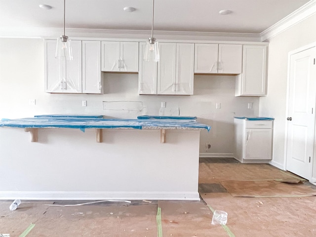 kitchen featuring white cabinetry, ornamental molding, a kitchen breakfast bar, and decorative light fixtures