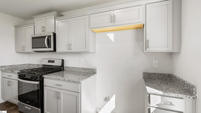 kitchen with light stone countertops, stainless steel appliances, white cabinets, and dark hardwood / wood-style floors