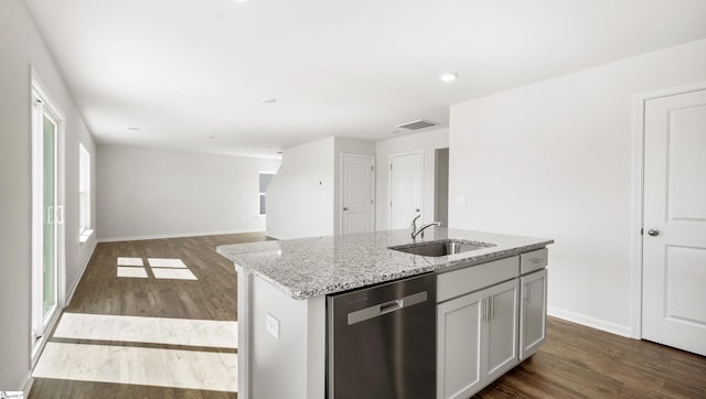 kitchen featuring a center island with sink, sink, stainless steel dishwasher, hardwood / wood-style flooring, and light stone countertops