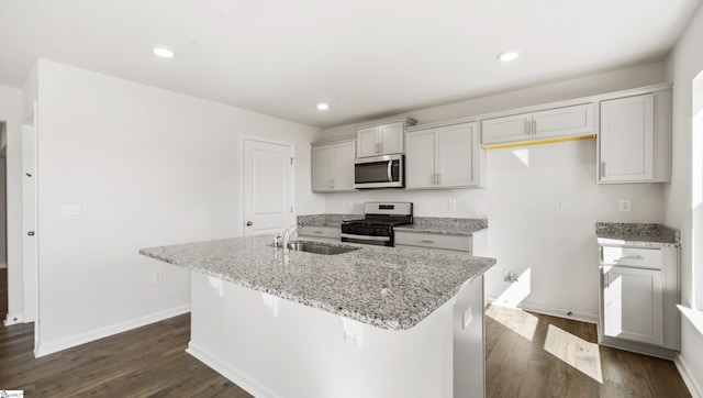 kitchen featuring light stone counters, gas range, a kitchen island with sink, dark wood-type flooring, and sink