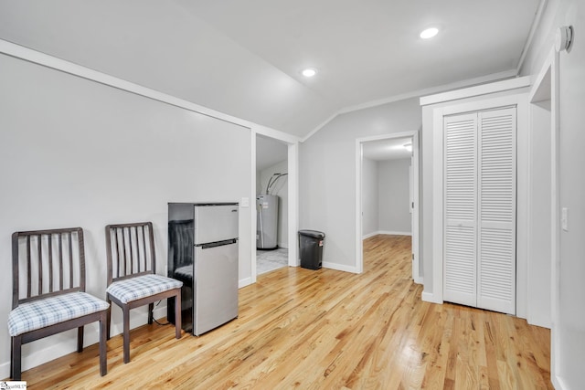 interior space featuring light hardwood / wood-style flooring, water heater, and lofted ceiling