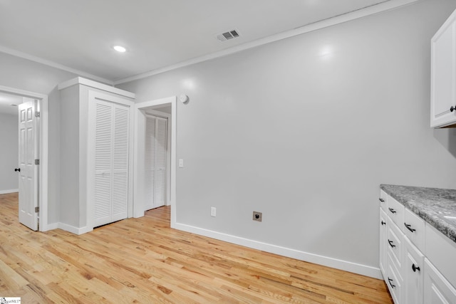 unfurnished bedroom with a closet, light wood-type flooring, and crown molding