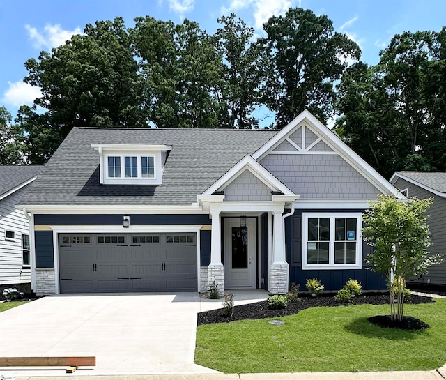 craftsman-style home featuring a shingled roof, concrete driveway, a front yard, a garage, and stone siding
