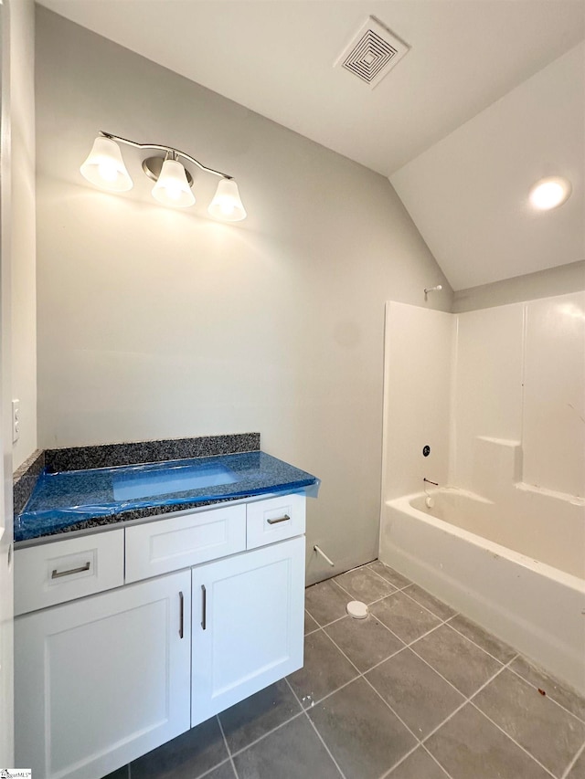 bathroom featuring visible vents, lofted ceiling, shower / bathtub combination, tile patterned floors, and vanity