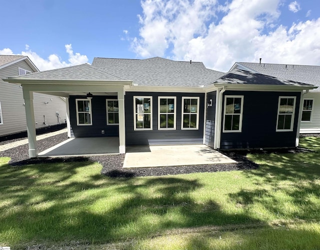 rear view of property featuring a shingled roof, a patio, a lawn, and ceiling fan