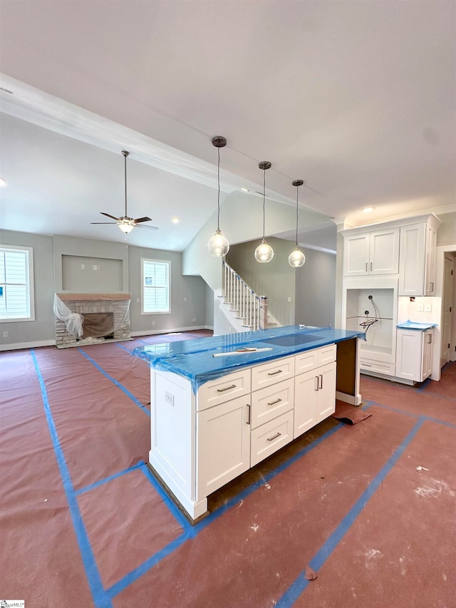 kitchen with dark countertops, white cabinetry, ceiling fan, vaulted ceiling, and hanging light fixtures