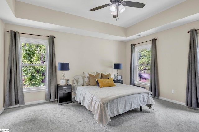 carpeted bedroom featuring ceiling fan and a raised ceiling