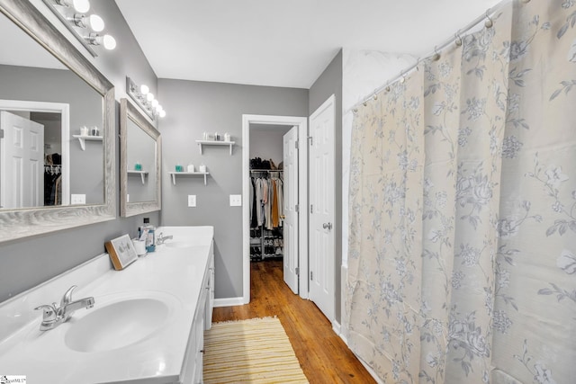 bathroom featuring vanity with extensive cabinet space, dual sinks, and hardwood / wood-style floors