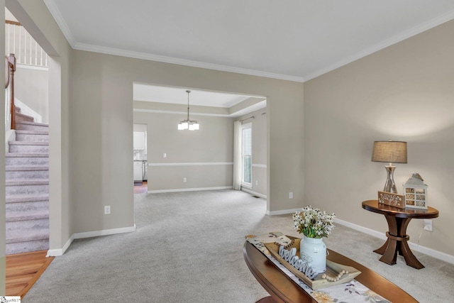 living room featuring carpet, ornamental molding, a tray ceiling, and a notable chandelier