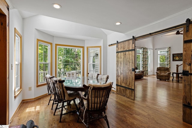 dining area featuring a healthy amount of sunlight, hardwood / wood-style floors, and a barn door