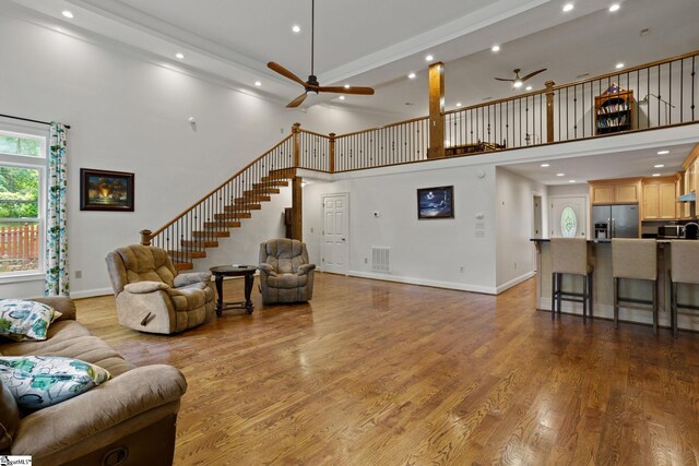 living room featuring light hardwood / wood-style floors, a high ceiling, and ceiling fan