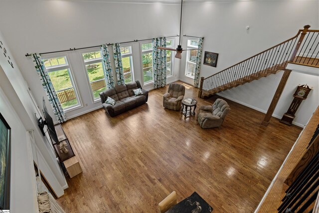 living room with a high ceiling, ceiling fan, and hardwood / wood-style floors