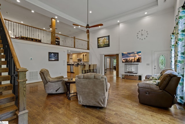 living room featuring wood-type flooring, a towering ceiling, and ceiling fan