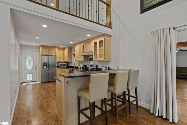 kitchen with a breakfast bar, hardwood / wood-style flooring, kitchen peninsula, and stainless steel appliances