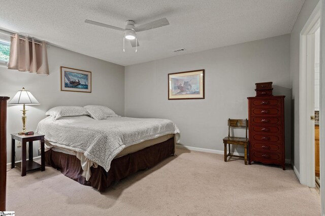 carpeted bedroom with ceiling fan and a textured ceiling