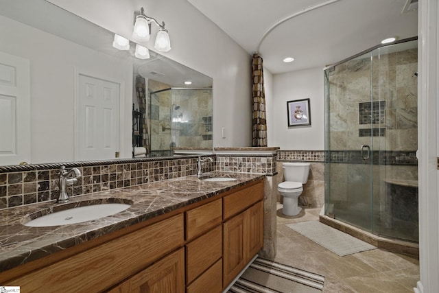 bathroom featuring tasteful backsplash, a shower with door, tile floors, dual bowl vanity, and toilet