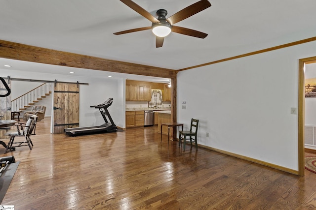 interior space with a barn door, crown molding, wood-type flooring, and ceiling fan