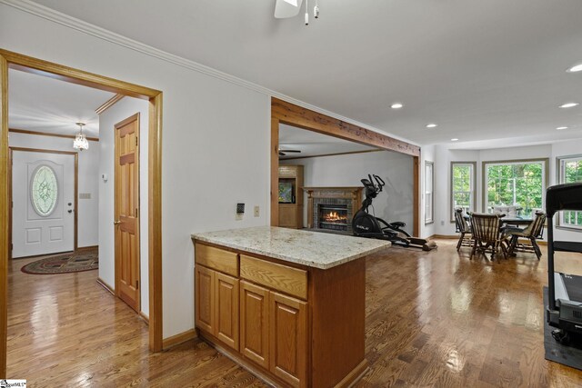 kitchen featuring crown molding, ceiling fan, light stone counters, and hardwood / wood-style flooring