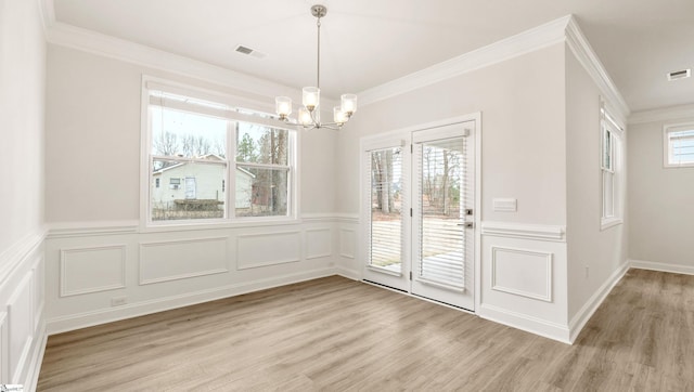 unfurnished dining area featuring crown molding, an inviting chandelier, and light hardwood / wood-style flooring