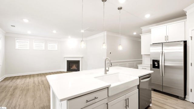 kitchen featuring sink, appliances with stainless steel finishes, a kitchen island with sink, hanging light fixtures, and white cabinets