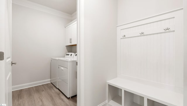 washroom featuring cabinets, crown molding, washer and dryer, and light hardwood / wood-style flooring