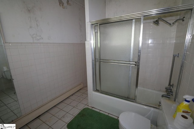 bathroom featuring shower / bath combination with glass door, a baseboard radiator, tile walls, toilet, and tile floors