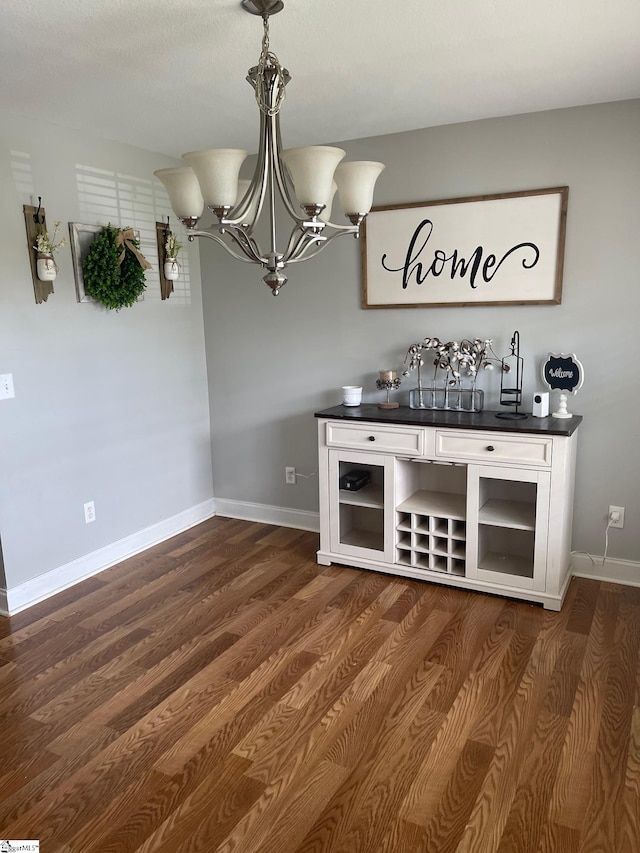 bar featuring an inviting chandelier, hanging light fixtures, white cabinetry, and dark hardwood / wood-style floors