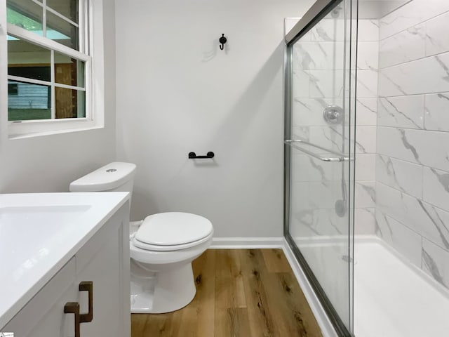 bathroom with a shower with shower door, wood-type flooring, vanity, and toilet