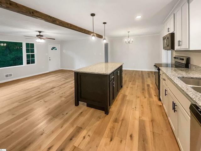 kitchen with ceiling fan with notable chandelier, hanging light fixtures, light wood-type flooring, white cabinets, and appliances with stainless steel finishes