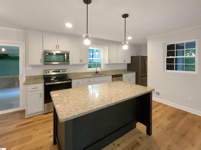 kitchen featuring decorative light fixtures, light hardwood / wood-style flooring, white cabinetry, appliances with stainless steel finishes, and sink