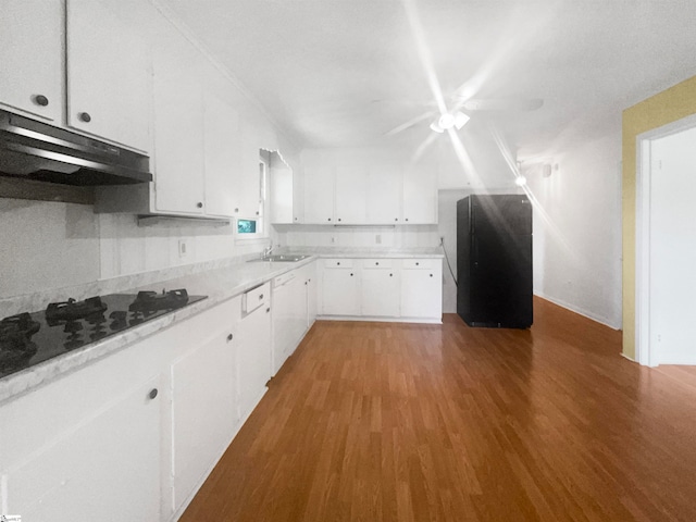 kitchen with black fridge, white cabinetry, hardwood / wood-style floors, sink, and tasteful backsplash